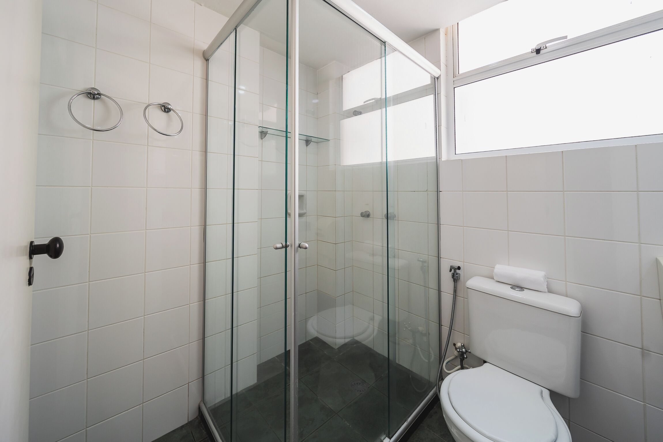 Une salle de bain moderne avec une douche à parois de verre, des toilettes et une étagère en verre.