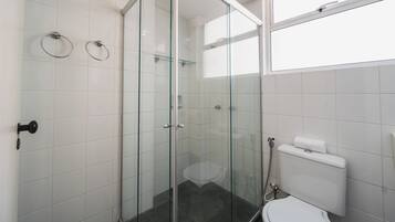 Une salle de bain moderne avec une douche à parois de verre, des toilettes et une étagère en verre.