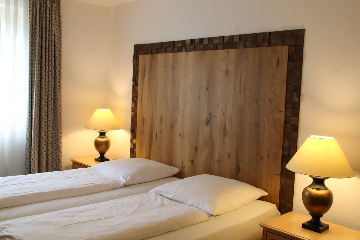 Une chambre d’hôtel avec deux lits, une tête de lit en bois et des lampes de chevet.