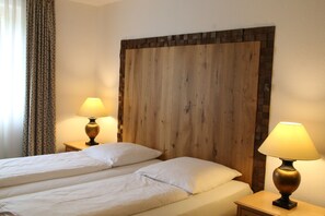 Une chambre d’hôtel avec deux lits, une tête de lit en bois et des lampes de chevet.