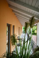 Um espaço ao ar livre coberto com parede amarela, escadaria e plantas altas.