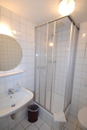 Un baño con lavamanos, espejo e inodoro blancos.