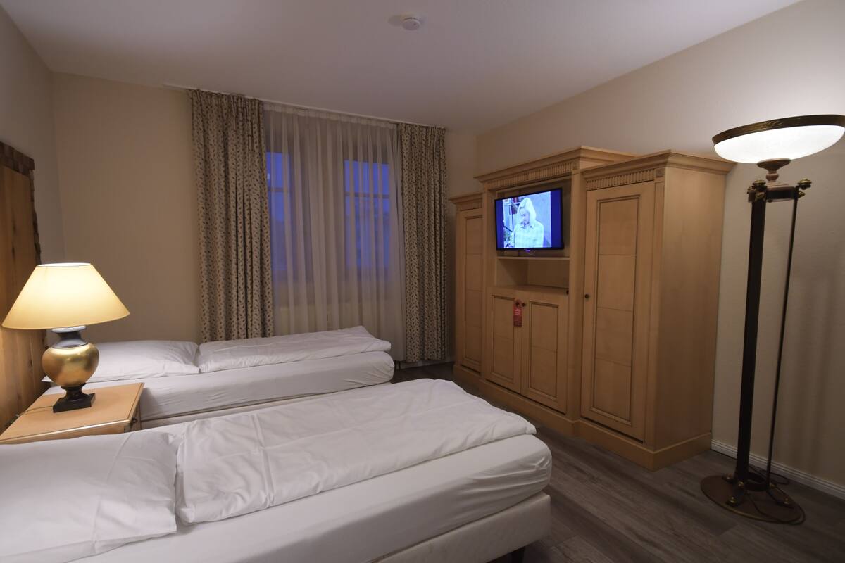 Une chambre d’hôtel avec deux lits, une télévision, une lampe et une armoire.