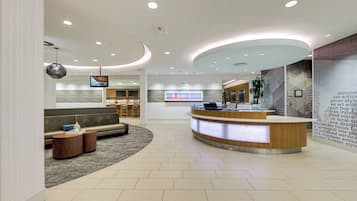 A modern reception area with a curved desk, seating area, and a large digital display.