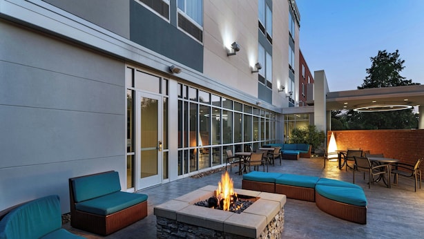 An outdoor patio with a fire pit, seating, and a glass-enclosed entrance.