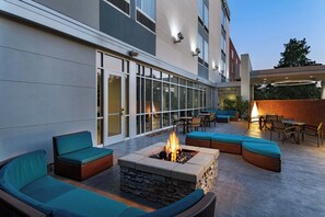 An outdoor patio with a fire pit, seating, and a glass-enclosed entrance. - SpringHill Suites Houston The Woodlands (The Woodlands)