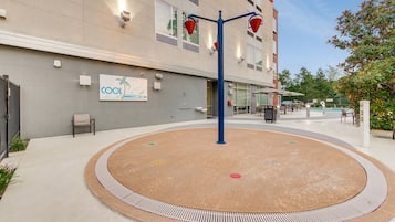 A hotel exterior with a sign reading "COOL" and a circular outdoor area with a blue pole and red buckets.