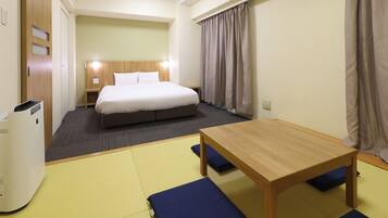 Een hotelkamer met een bed, een houten tafel en een futon.
