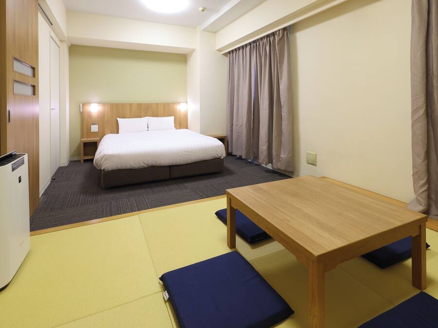 Een hotelkamer met een bed, een houten tafel en een futon.