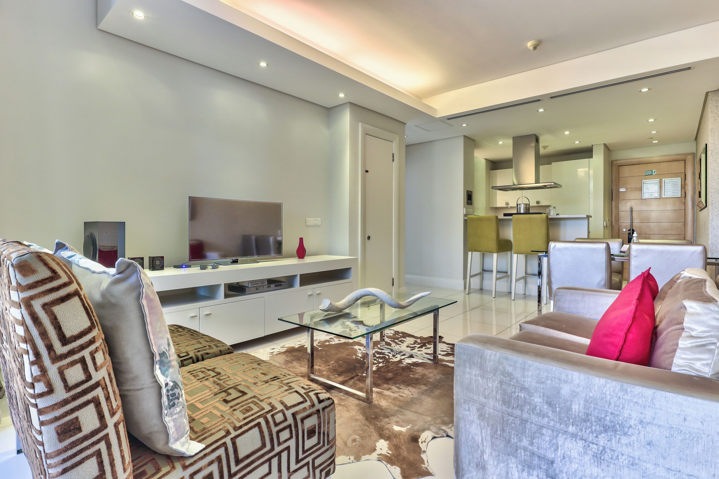 A modern living room with a sofa, a glass coffee table, and a patterned rug.