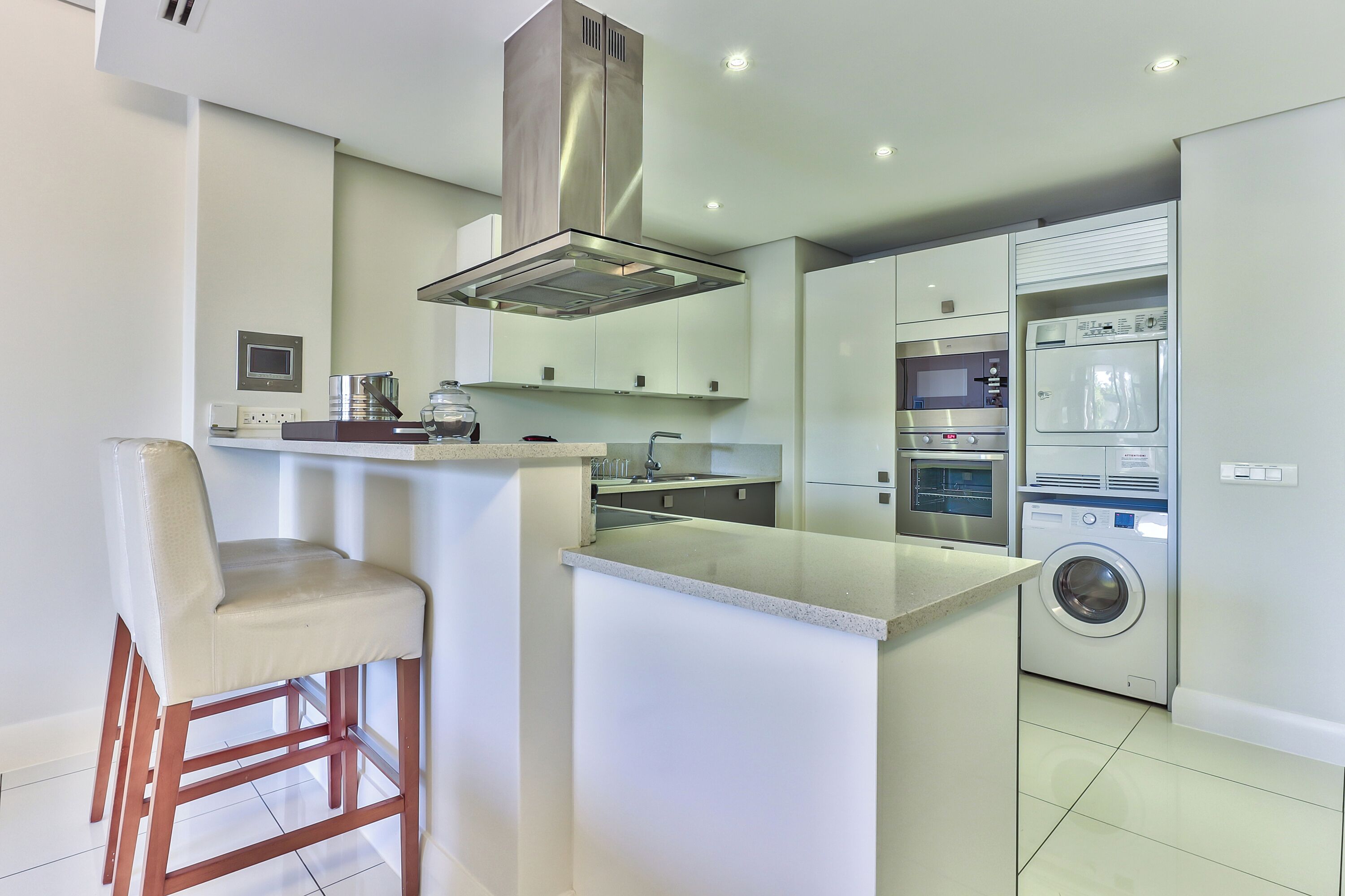 Een moderne keuken met een centraal eiland, roestvrijstalen apparatuur en een ingebouwde wasmachine.