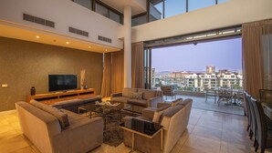 Una sala de estar moderna con una televisión de pantalla plana, sofás, una mesa de centro y un balcón con vistas a la ciudad.