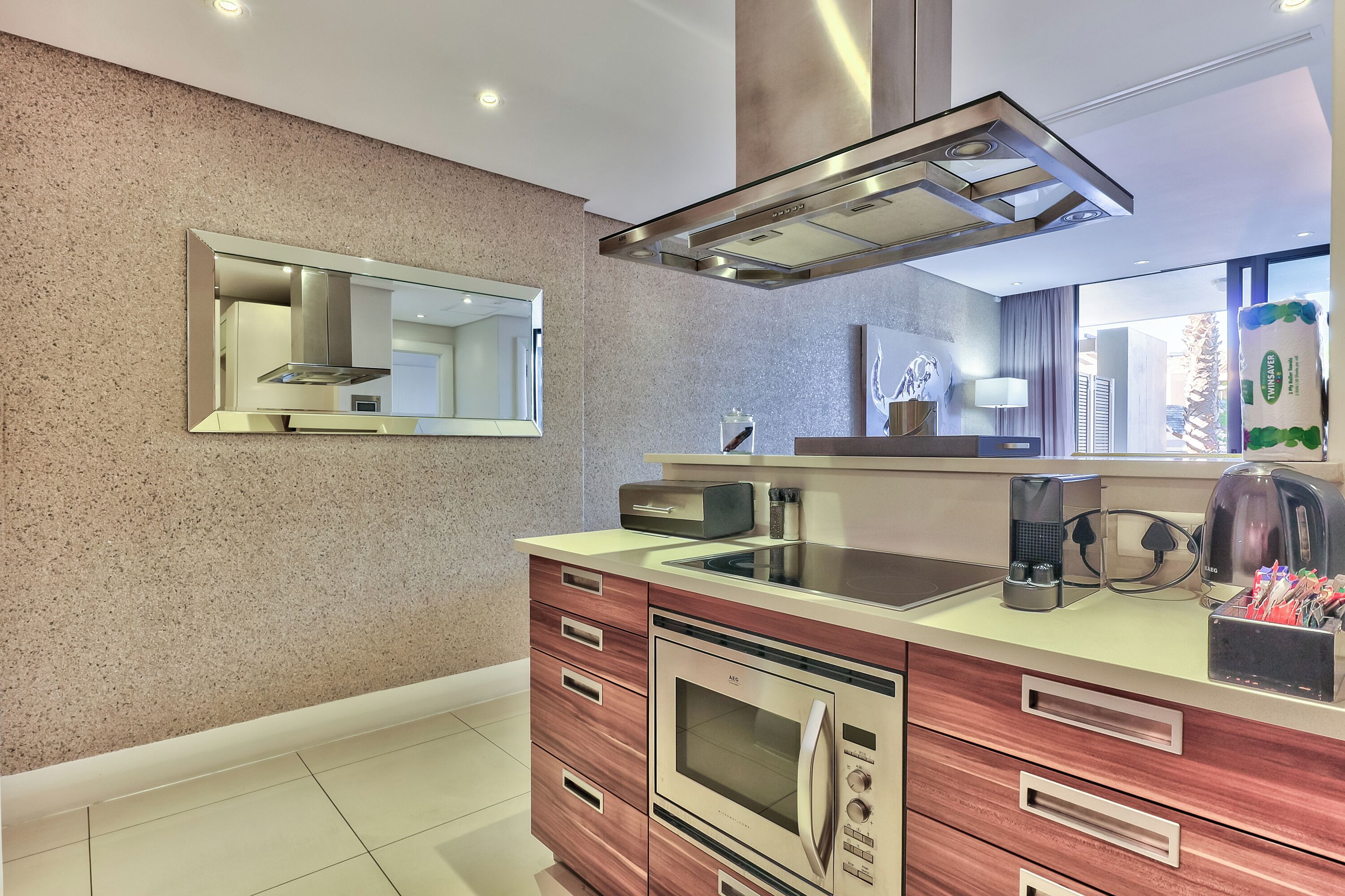 A modern kitchen with a built-in oven, a coffee maker, and a kettle on the counter.