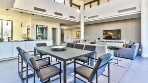 Amplia sala de estar moderna con una mesa de comedor, asientos y una cocina al fondo.