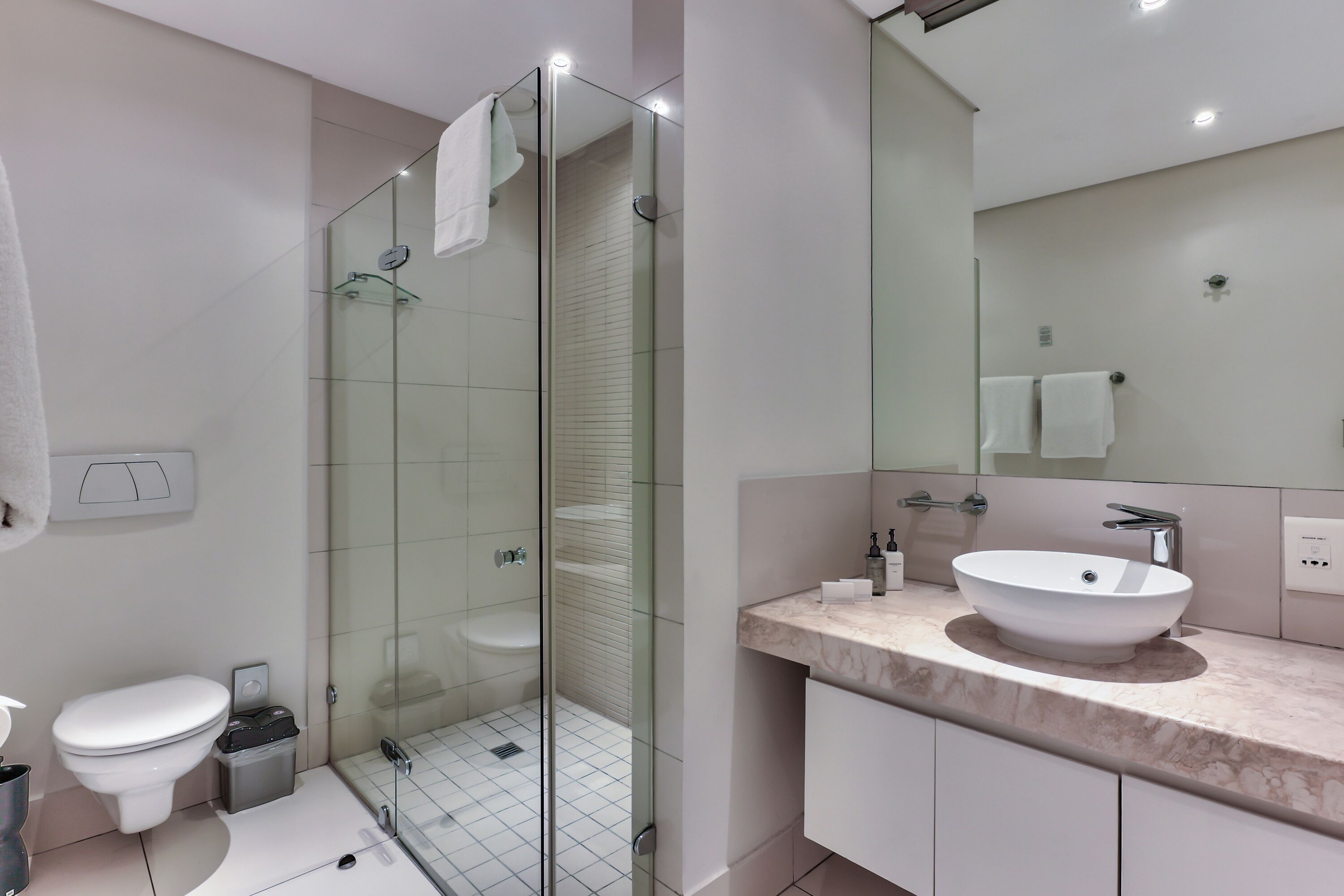 A modern bathroom with a glass-enclosed shower, a white sink, and a large mirror.