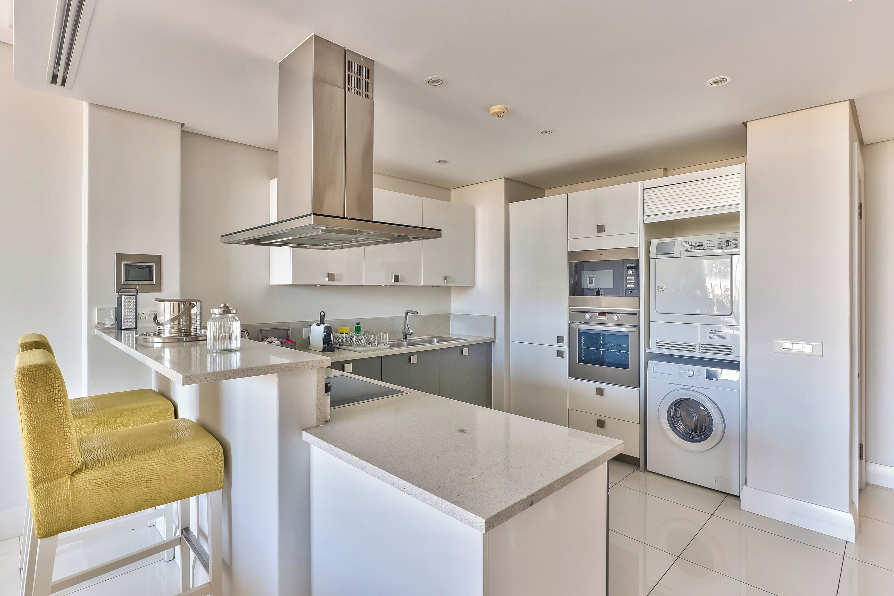 Una cocina moderna con una isla central, electrodomésticos integrados y un taburete de bar.