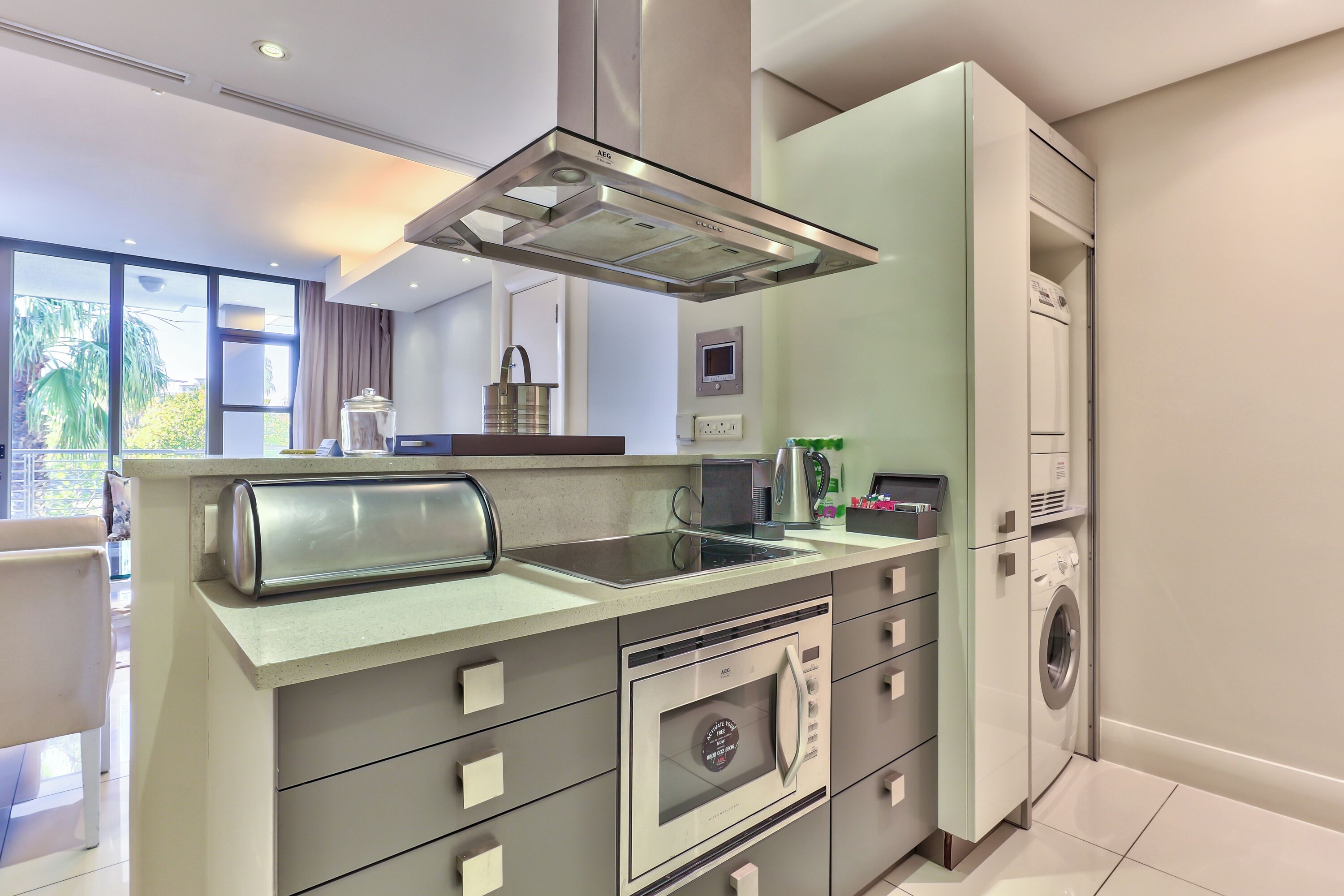 A modern kitchen with a built-in oven, microwave, and a washing machine in the adjacent space.