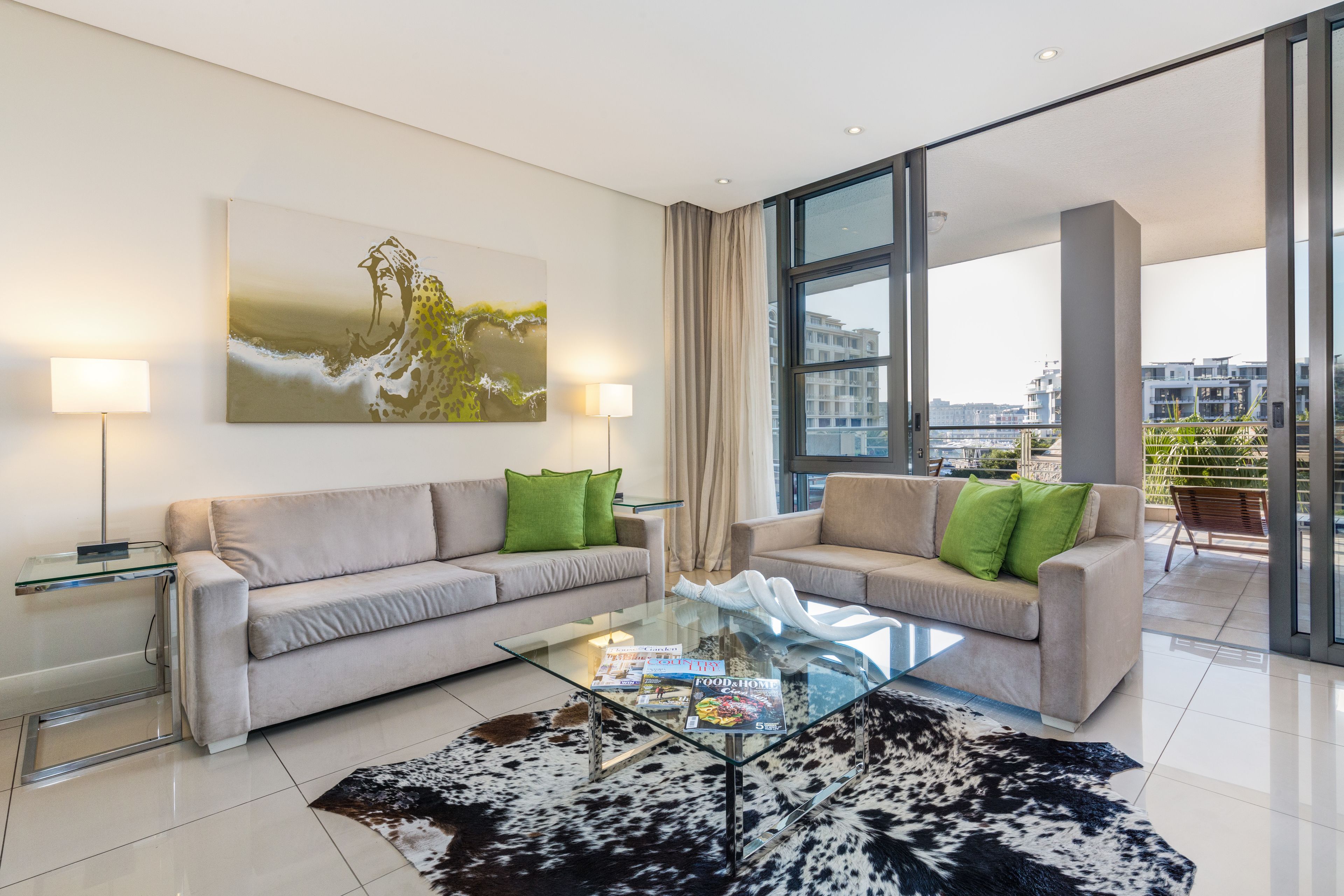 A modern living room with two sofas, a glass coffee table, and a large window offering a city view.