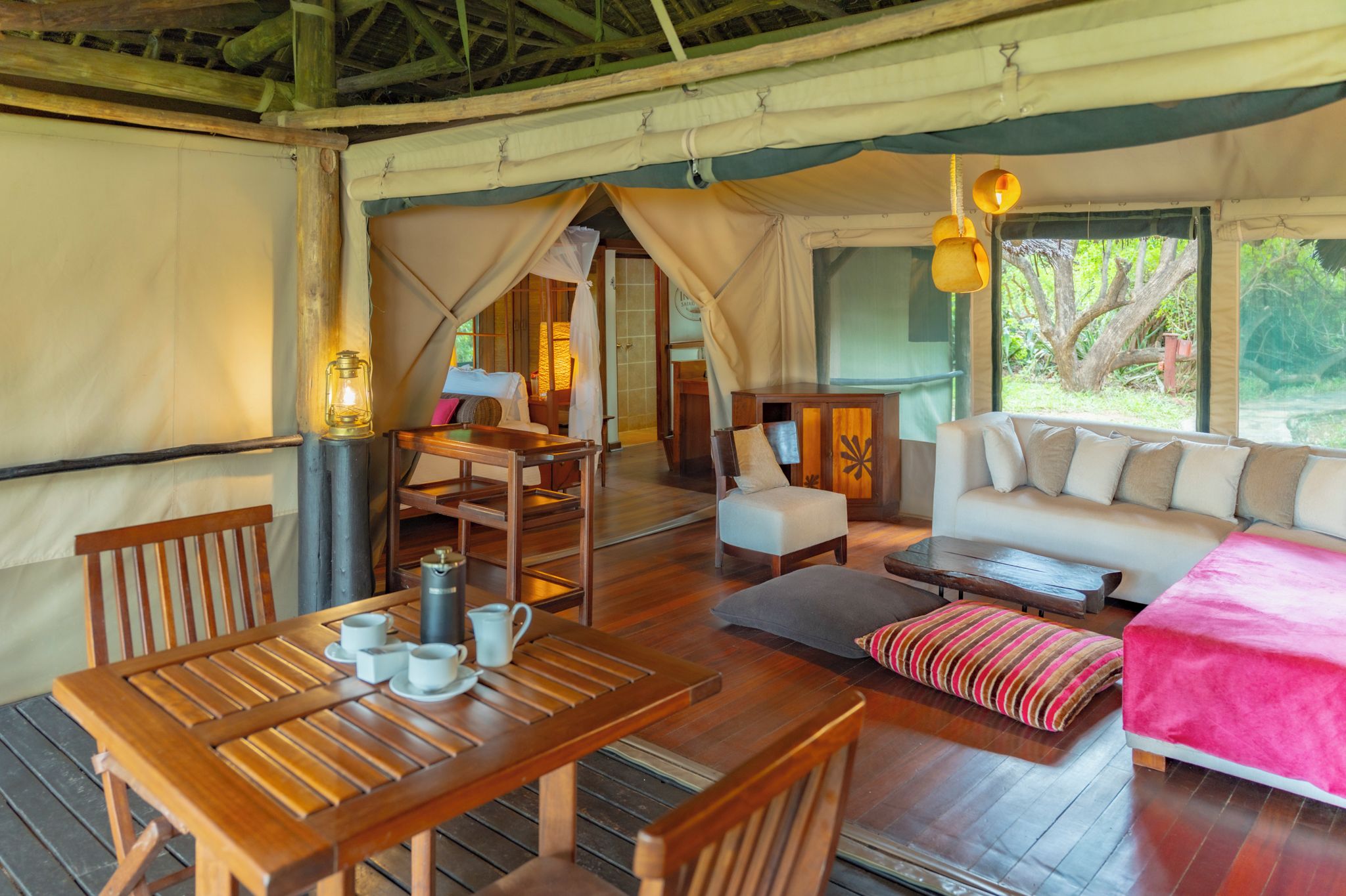 A tented accommodation with a dining area, a sofa, and a bed.