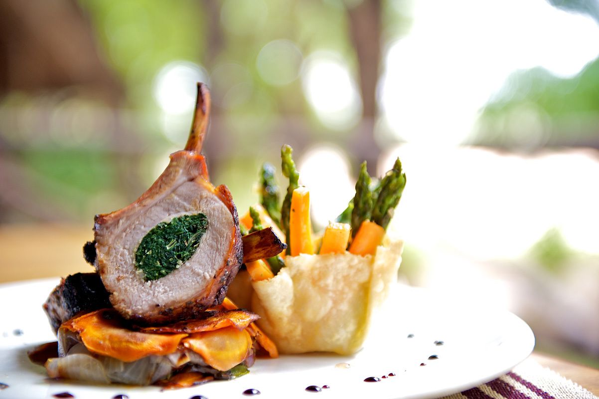 Une assiette comprenant une côte d’agneau, des asperges et une petite portion de purée de pommes de terre.