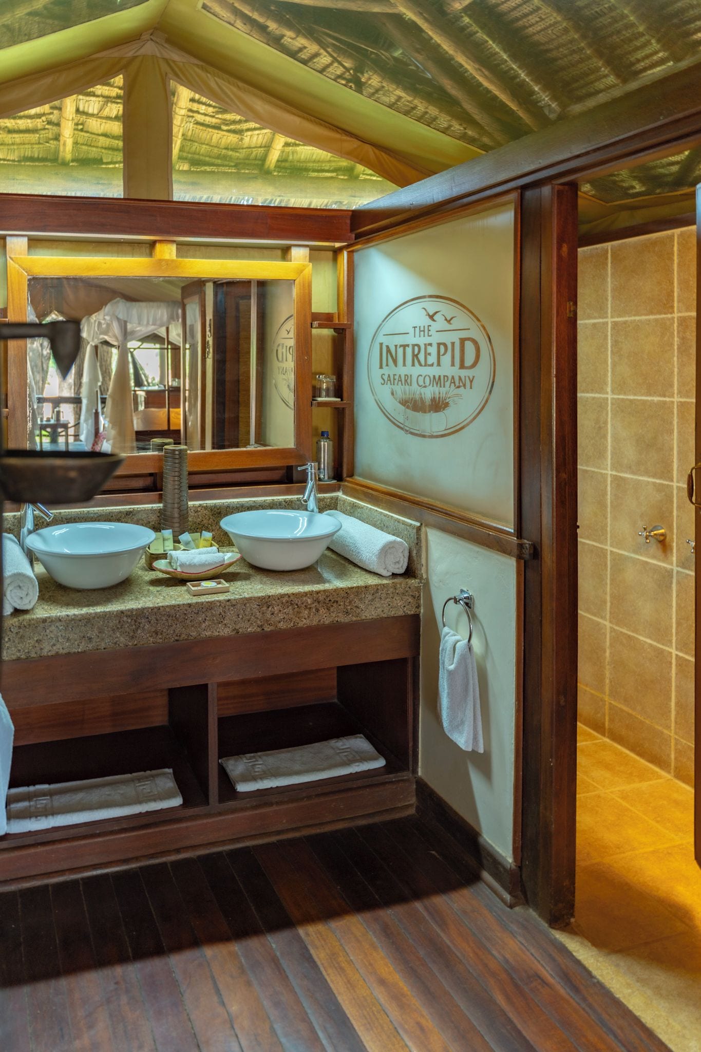 Un baño con tocador de madera, dos lavamanos, un espejo y zona de ducha.