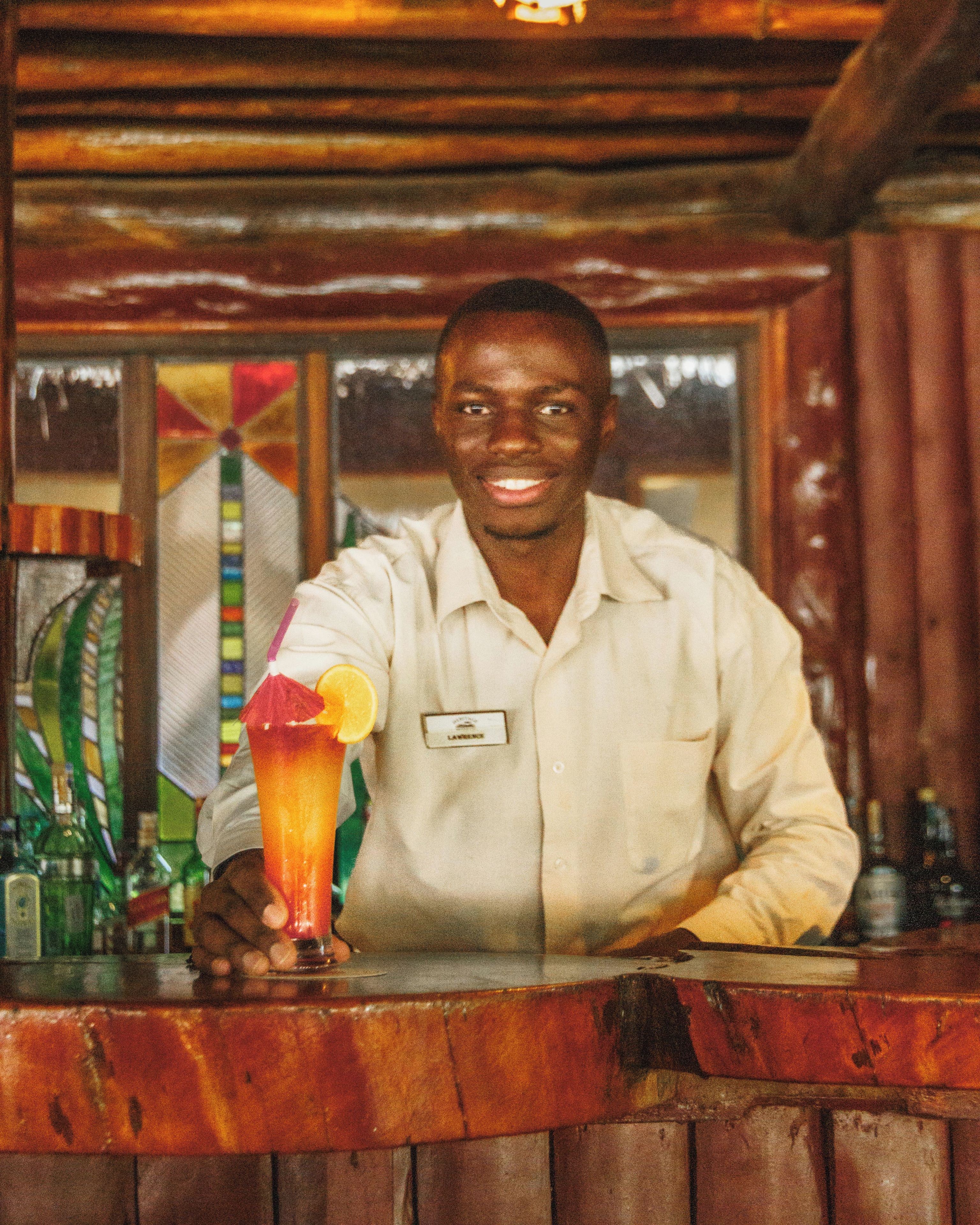 A person standing behind a bar counter with a drink in hand.