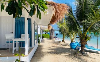 A beachside hotel with a covered veranda, a pool, and a view of the ocean.