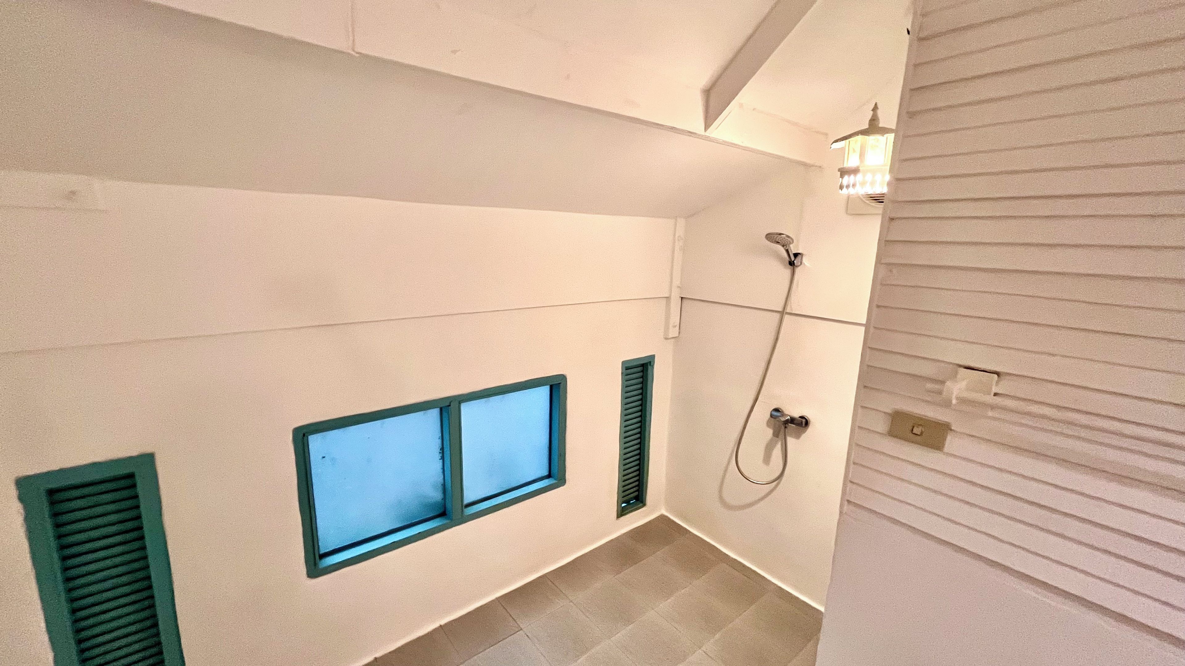 Un baño con ducha, ventana y lámpara.
