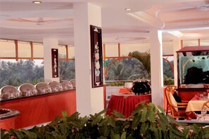 A restaurant with a long counter, red tablecloths, and a ceiling fan.