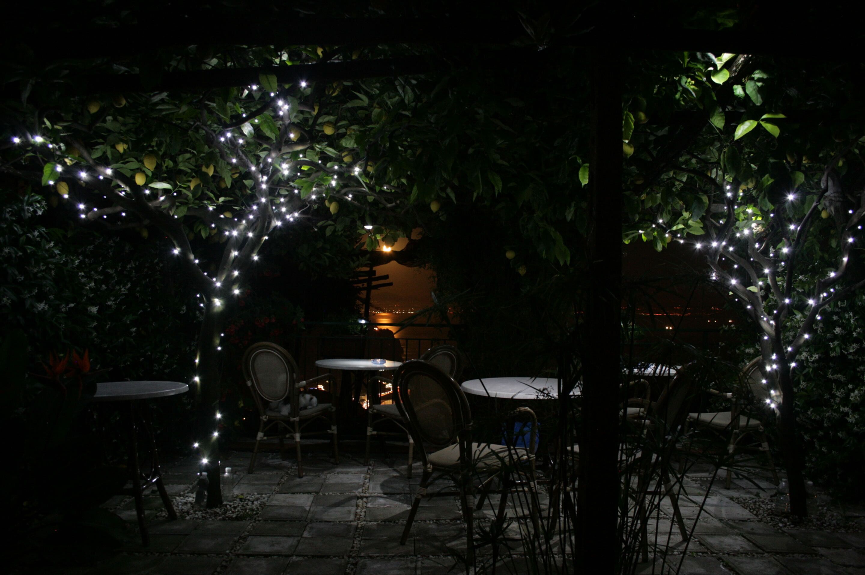 An outdoor patio area with tables and chairs, decorated with string lights.