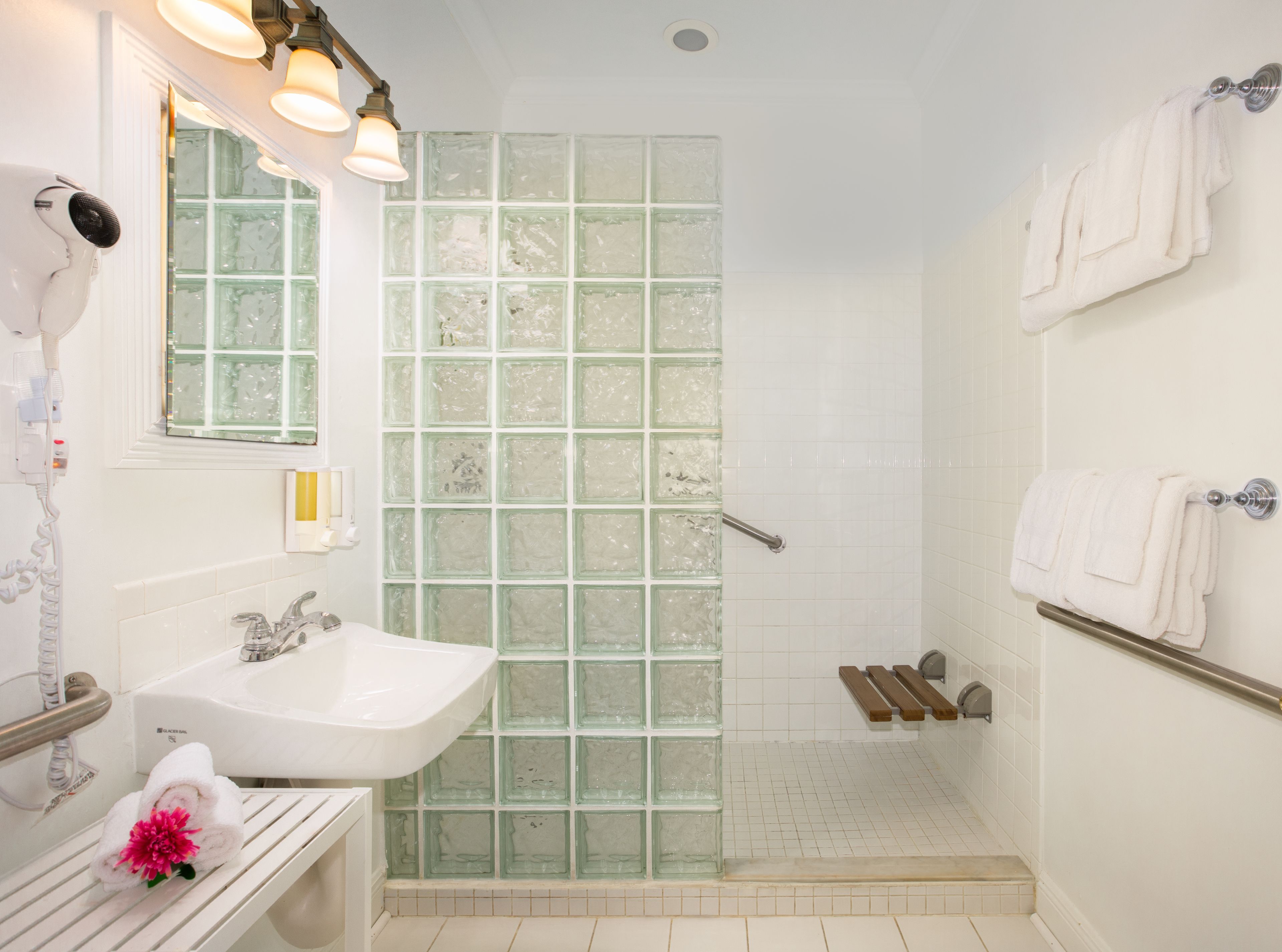 A bathroom with a glass shower enclosure, a sink, and a towel rack.