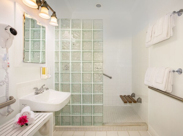 A bathroom with a glass shower enclosure, a sink, and a towel rack.