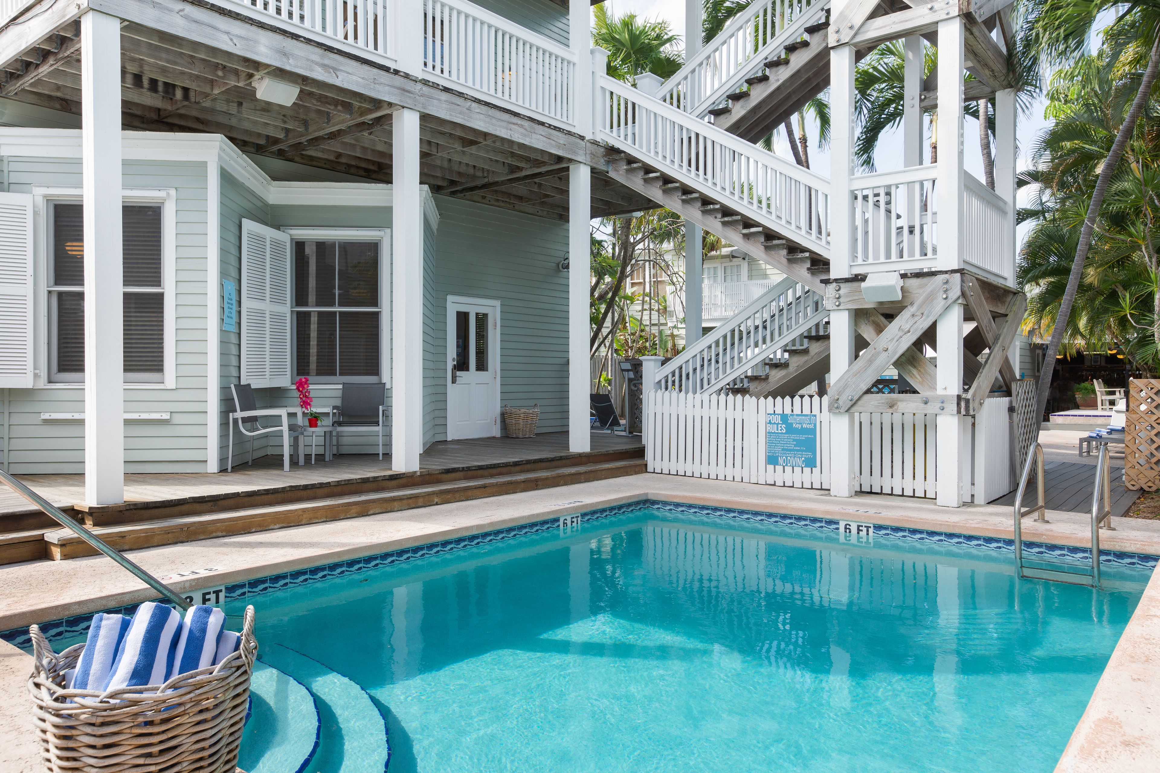 A pool area with a wooden deck, a staircase, and a sign indicating a 6 ft depth.