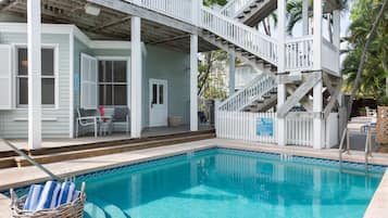 A pool area with a wooden deck, a staircase, and a sign indicating a 6 ft depth.