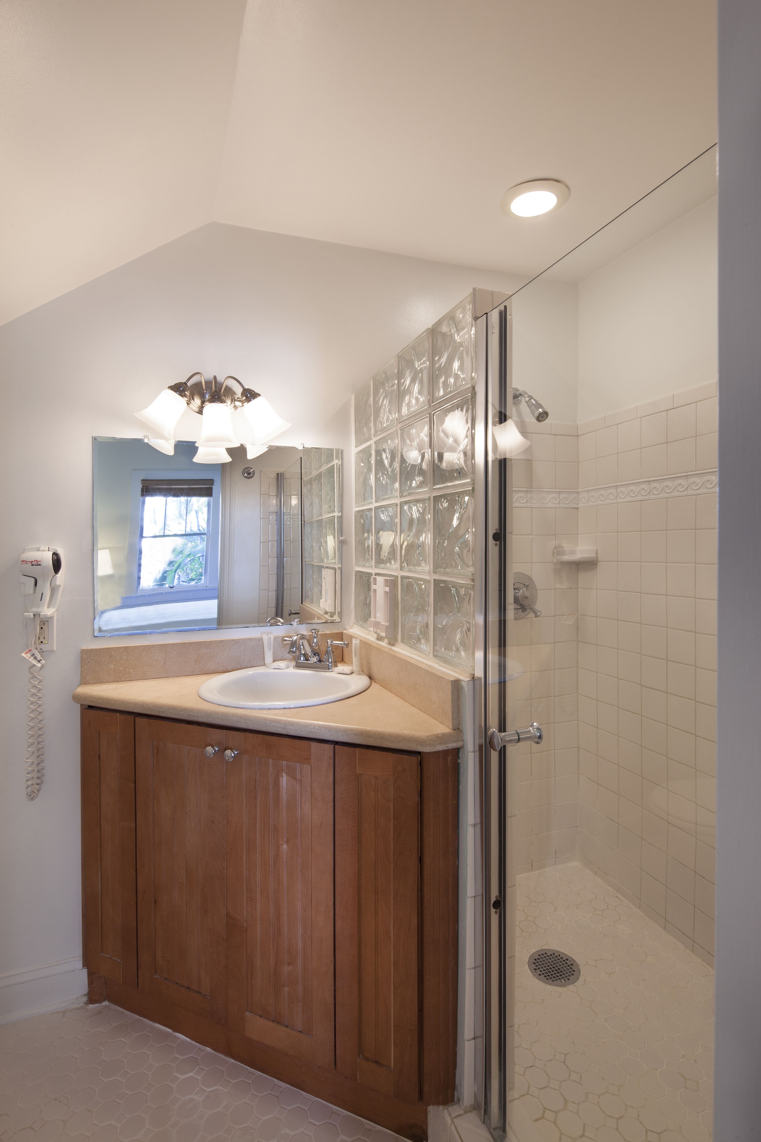 A bathroom with a glass shower enclosure, a sink with a vanity, and a window providing natural light.