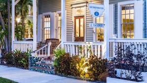 A Southernmost Inn with a porch, a sign indicating vacancy, and a staircase leading to the entrance. - The Southernmost Inn - Adults Only (Key West)
