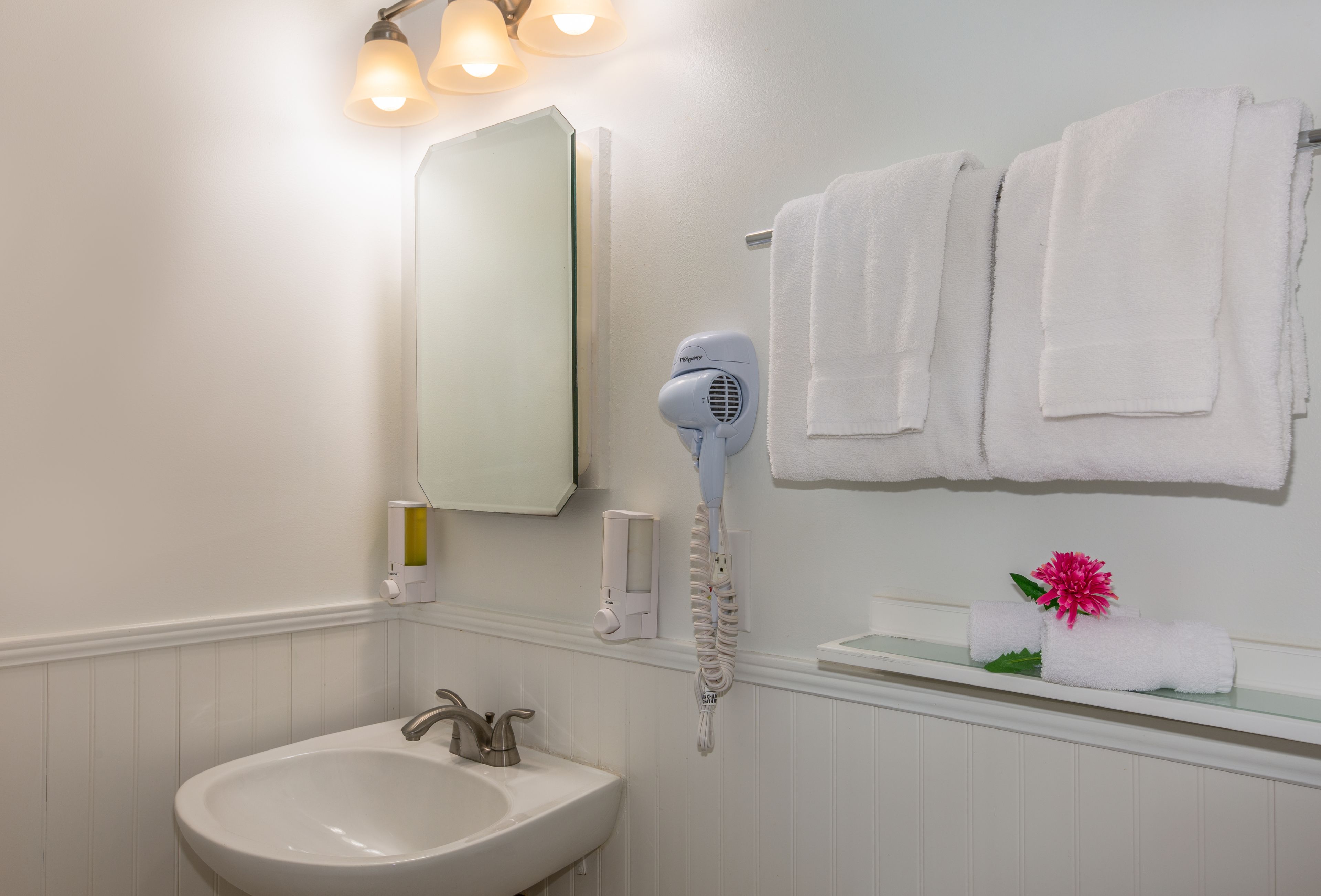 A bathroom with a sink, mirror, towel rack, and hair dryer.