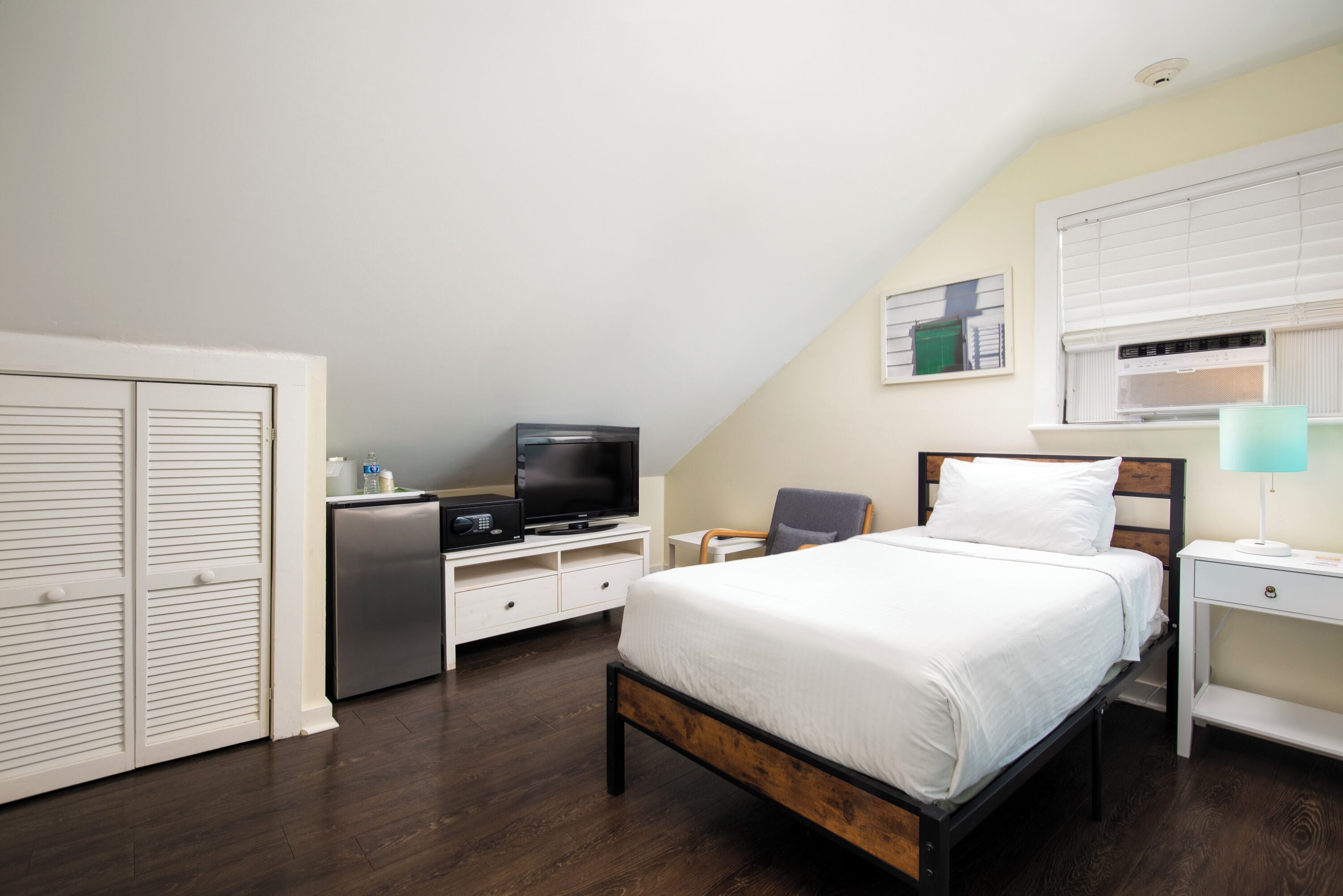 A bedroom with a bed, a television, a desk, and a chair.