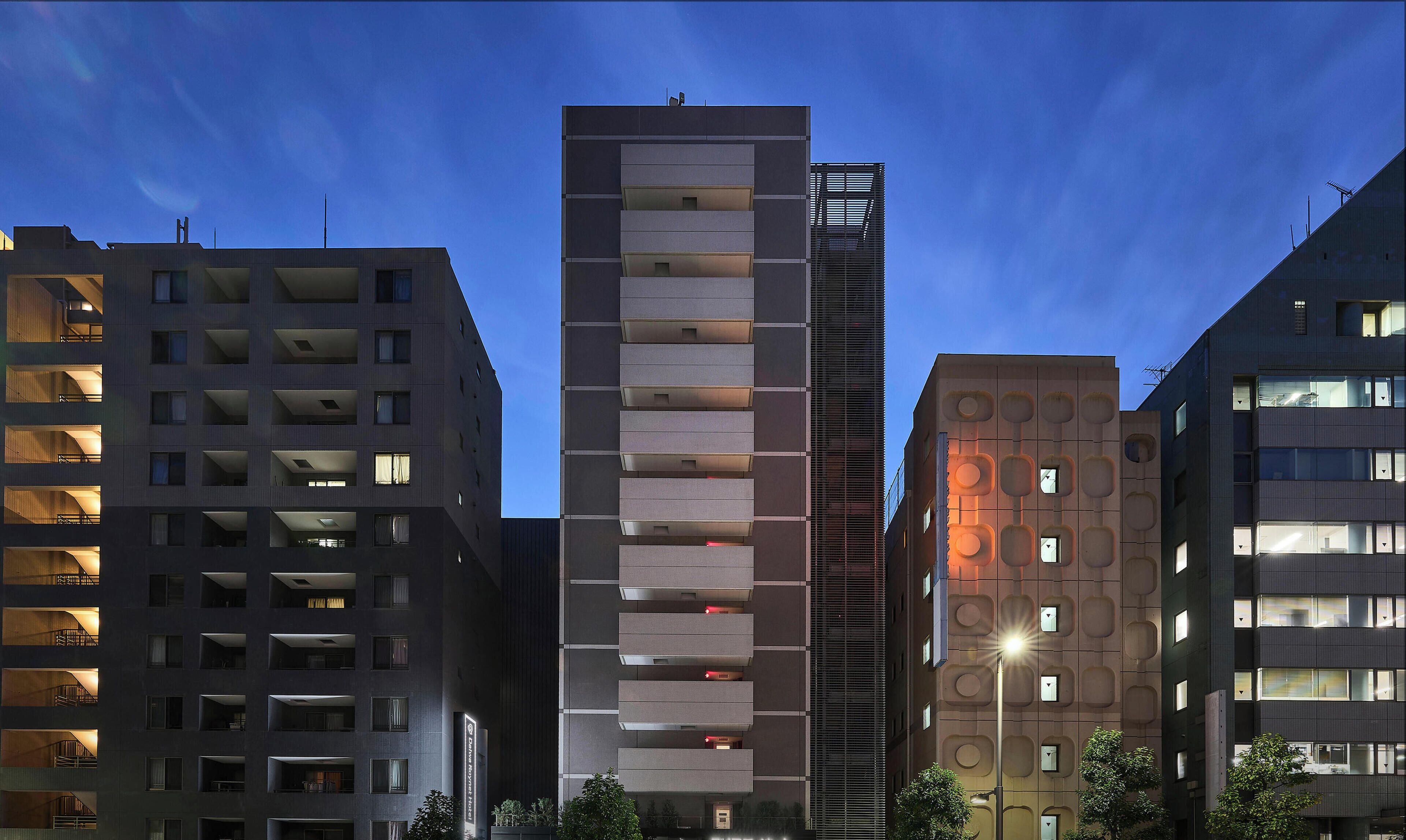 A modern high-rise building with multiple floors, balconies, and a central tower.