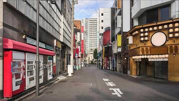 A narrow urban street lined with multi-story buildings, some with commercial establishments on the ground floor.