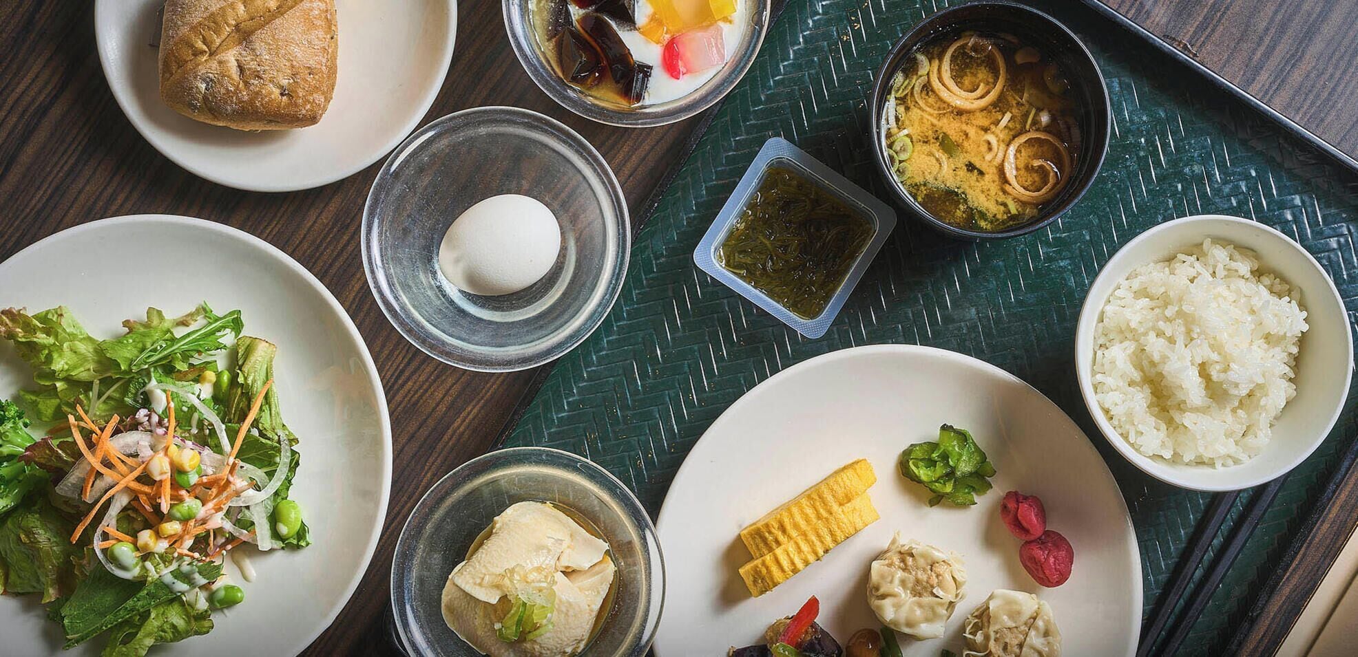 Una variedad de platos, entre ellos una ensalada, arroz, dumplings y una sopa, sobre una mesa.