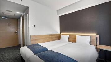 Habitación de hotel con una cama grande, una mesita de noche, una lámpara de pared y una puerta.