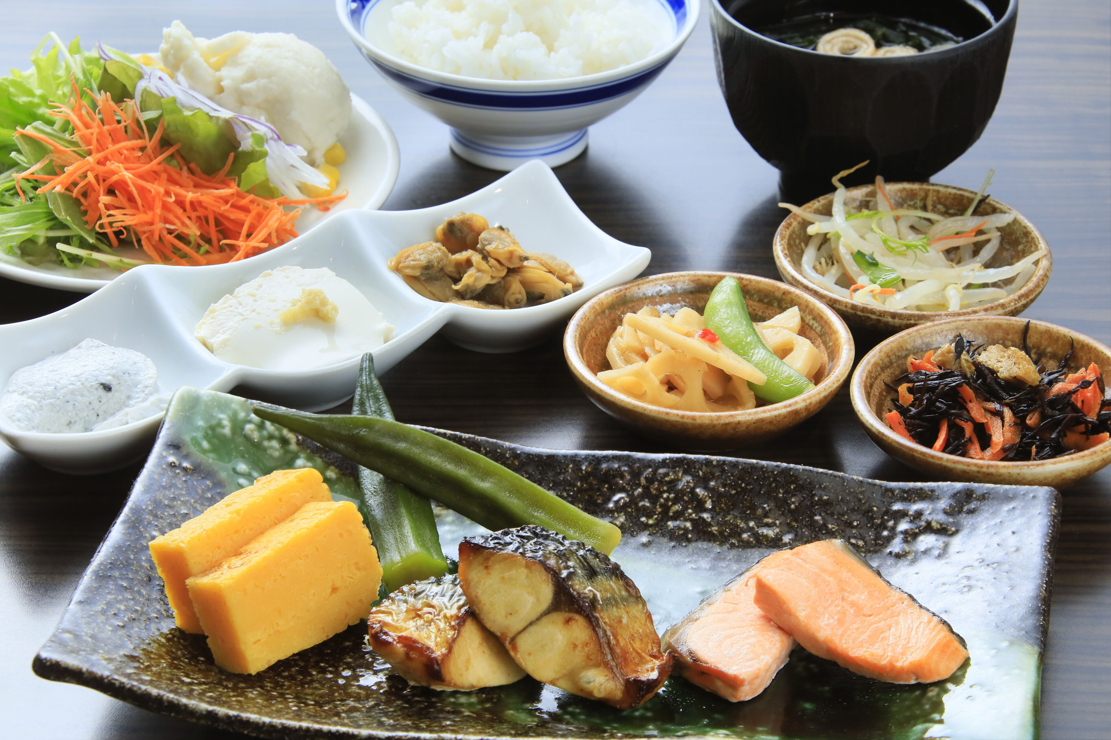 Una variedad de platos que incluyen salmón, verduras y arroz, dispuestos sobre una mesa.