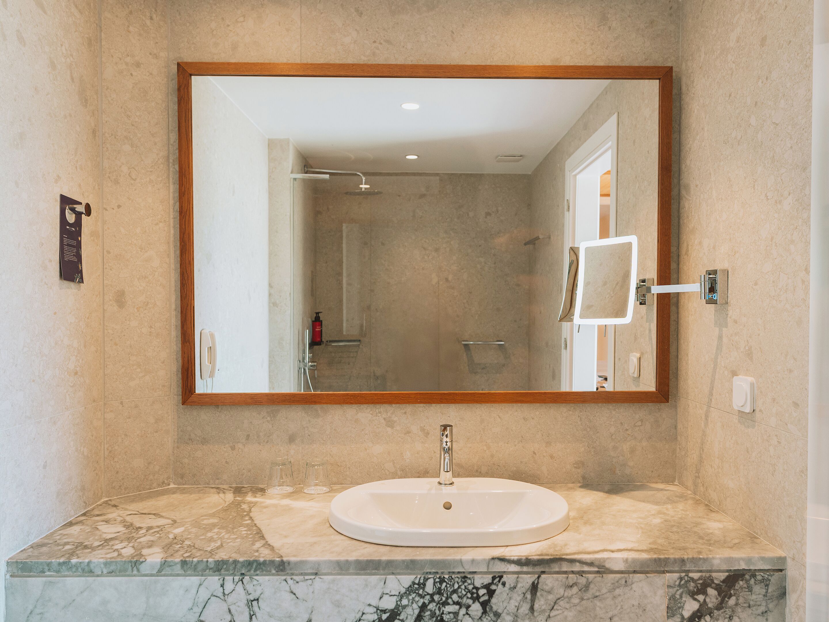 A bathroom with a marble sink, a large mirror, and a shower.