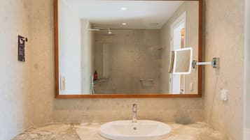 A bathroom with a marble sink, a large mirror, and a shower.