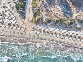 Na praia, espreguiçadeiras, guarda-sóis, toalhas de praia 