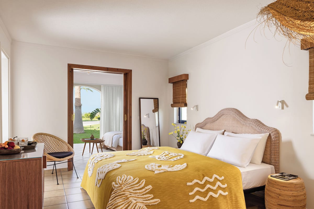 A hotel room with a bed, a desk, a chair, a small table, and a view of the outdoors.