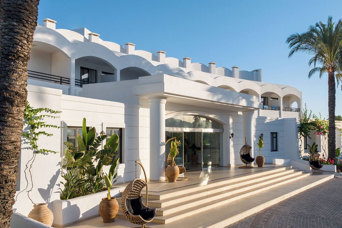 A modern building with a white facade, large columns, and a welcoming entrance with steps leading up to it.