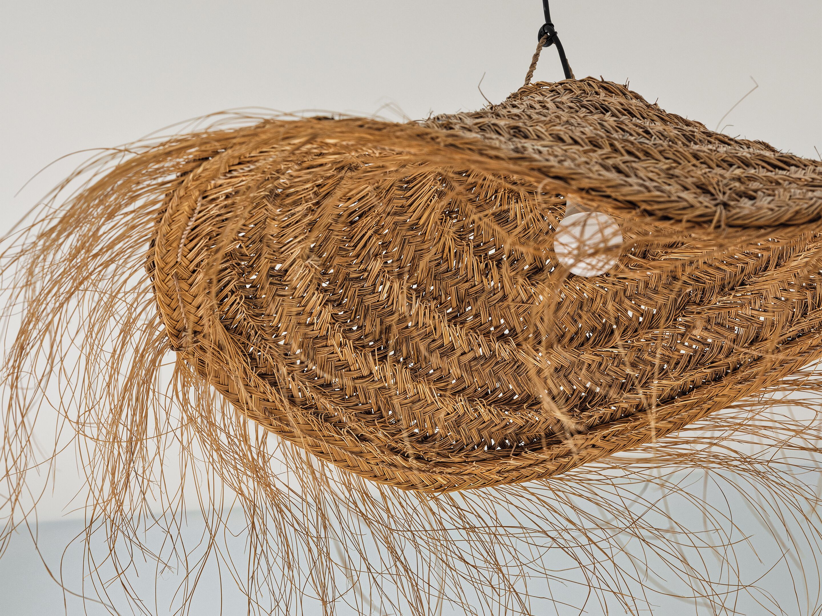 A woven hanging light fixture with a spherical object in the center.