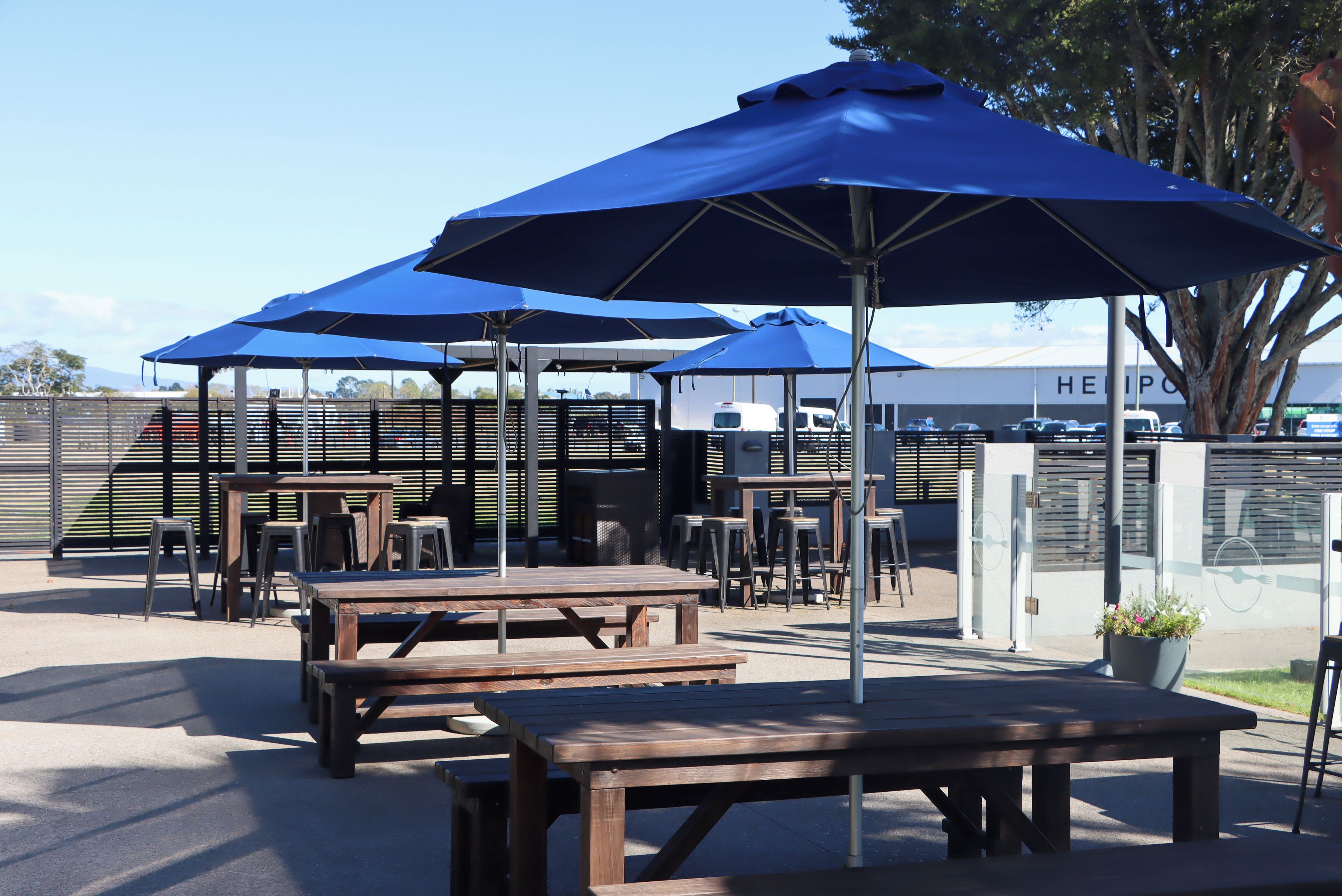 Espace extérieur aménagé avec des tables et des parasols bleus.
